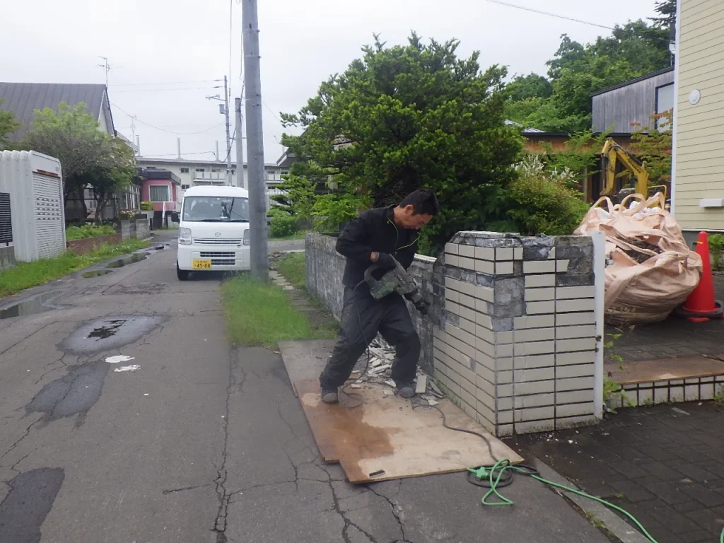 江別市一般住宅の塀を電動ピックで解体している様子（道路沿い）